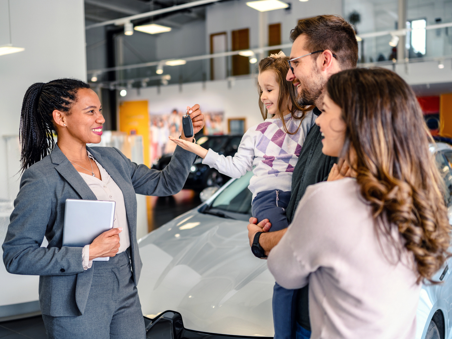 Sales person giving car key to family in car dealership